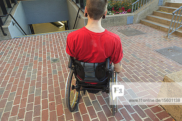 Trendy man with a spinal cord injury in wheelchair planning his access to the subway