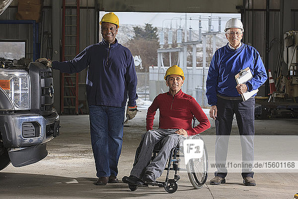Ingenieure  einer mit Rückenmarksverletzung  und Betreuer in der Garage des Elektrizitätswerks