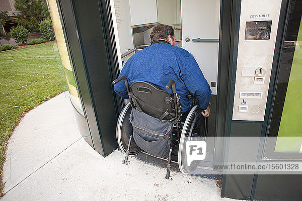 Mann im Rollstuhl mit Rückenmarksverletzung beim Betreten einer öffentlichen  kostenpflichtigen Toilette