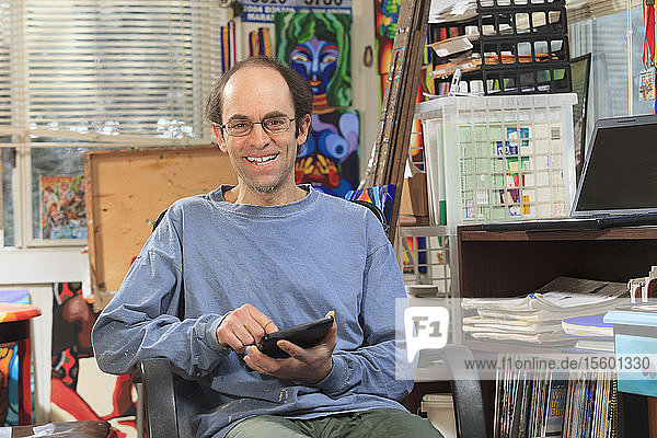 Mann mit Asperger-Syndrom bei der Arbeit an seinem Tablet in seinem Kunstatelier