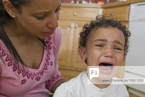 Besorgte hispanische Mutter neben ihrem weinenden Sohn