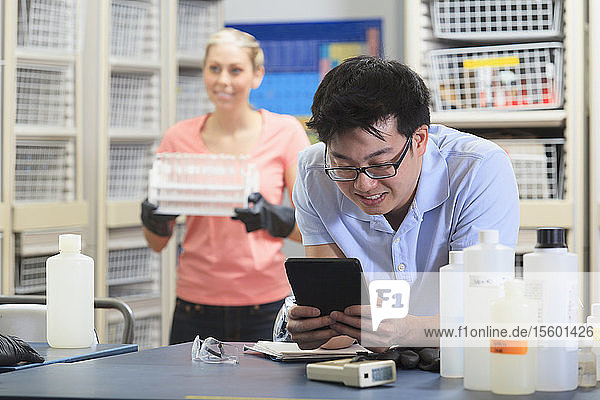 Engineering student using a tablet to record data in chemistry laboratory