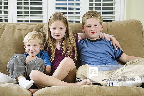 Portrait of three children sitting on a sofa.