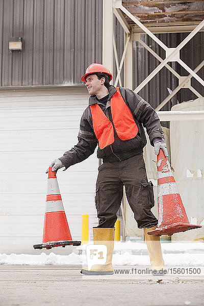 Verkehrsingenieur beim Verschieben von Verkehrsleitkegeln auf einer Baustelle