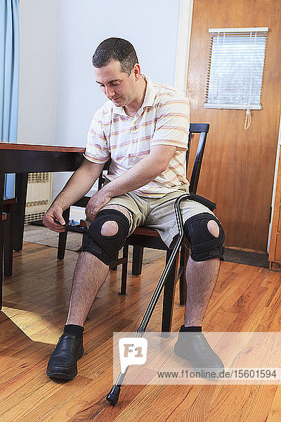 Mann  der nach einer Operation des vorderen Kreuzbandes (ACL) seine Kniestütze anpasst