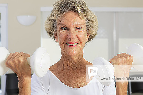 Porträt einer älteren Frau  die mit Gewichten trainiert