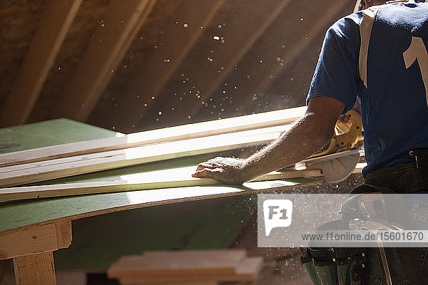 Spanischer Zimmermann bei der Arbeit mit der Kreissäge an einer Zierleiste in einem im Bau befindlichen Haus