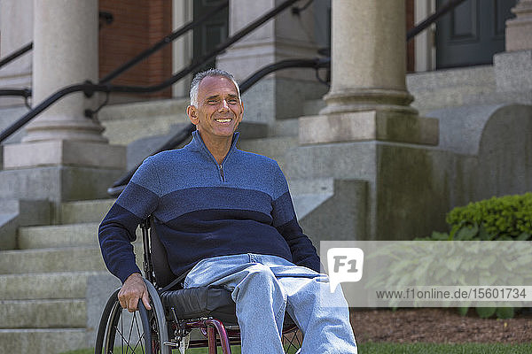 Mann mit Rückenmarksverletzung sitzt in einem Rollstuhl und lächelt