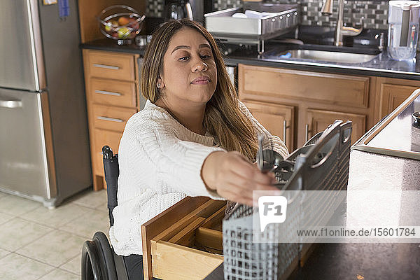 Woman with Spinal Cord Injury arranging dishwasher