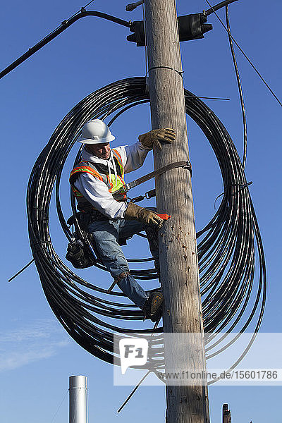 Kabelmonteur bei der Vorbereitung der Verlegung eines neuen Kabels vom Strommast