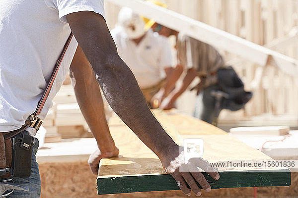 Zimmerleute halten eine Planke auf einer Baustelle