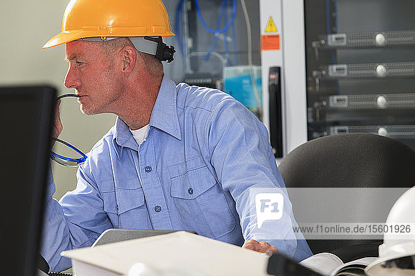 Electrical engineer studying monitor for performance in operations room of electric power plant