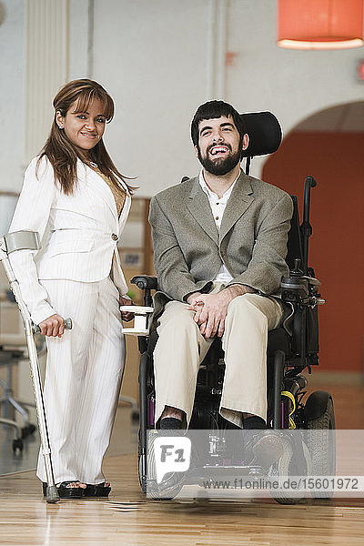 Porträt einer Frau  die neben einem Mann mit zerebraler Lähmung im Rollstuhl steht.