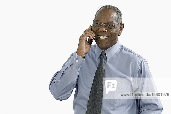 Nahaufnahme eines Geschäftsmannes  der lächelnd mit einem Mobiltelefon spricht