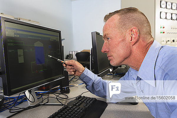 Ingenieur in der Leitwarte eines Elektrizitätswerks  der die Messwerte auf den Management-Displays überprüft
