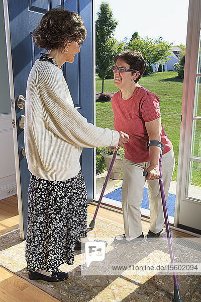 Frau mit zerebraler Lähmung begrüßt jemanden an der Tür