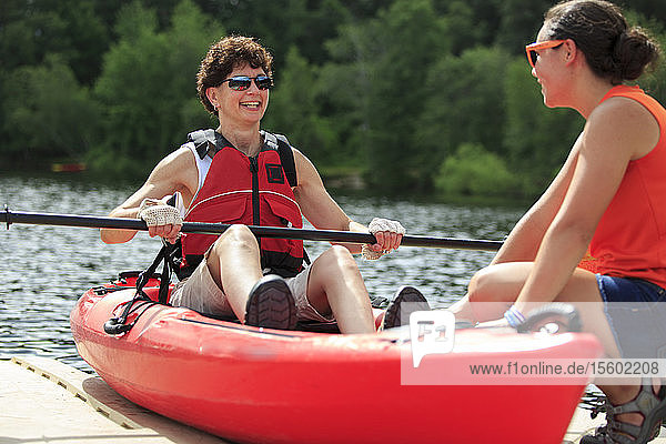 Instructor helping a woman with a Spinal Cord Injury with using a kayak