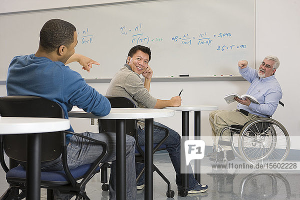 Universitätsprofessor mit Muskeldystrophie  der auf einen Studenten in einem Klassenzimmer zeigt