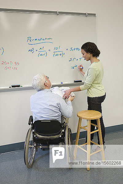 Universitätsprofessor mit Muskeldystrophie unterrichtet seine Studenten in einem Klassenzimmer