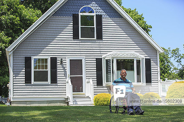 Mann mit einer Rückenmarksverletzung im Rollstuhl vor seinem Haus
