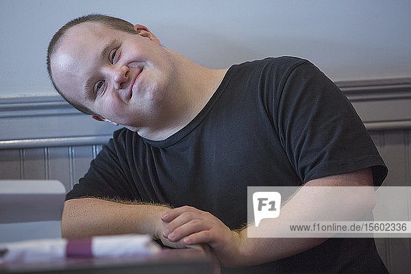 Porträt eines Kellners mit Down-Syndrom  der in einem Restaurant sitzt