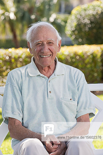 Portrait of an elder man sitting on a park bench and smiling