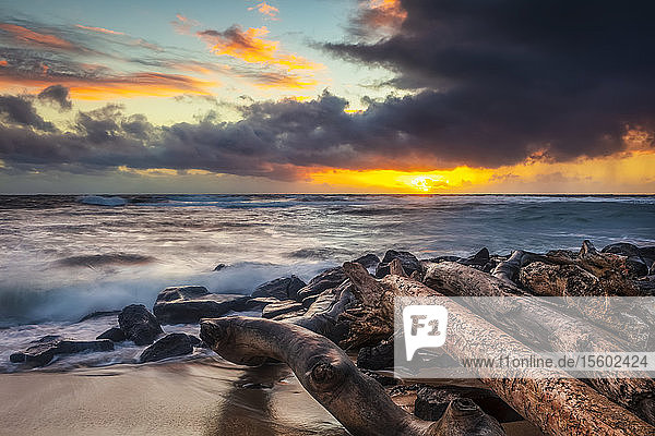 Sonnenaufgang über Strand und Meer mit einer Sturmwolke und Regen in der Ferne; Kauai  Hawaii  Vereinigte Staaten von Amerika