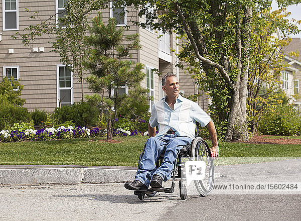 Man with spinal cord injury in a wheelchair crossing at accessible street entrance