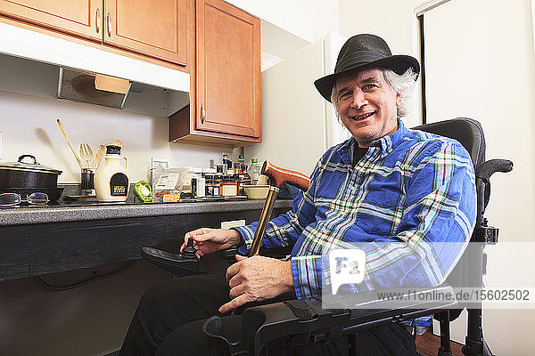 Mann mit Multipler Sklerose im Rollstuhl sitzt in seiner barrierefreien Küche