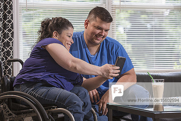 Frau mit Spina Bifida und ihr Mann sehen sich zu Hause eine Textnachricht an