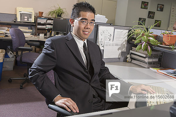 Portrait of happy Asian man with Autism working on computer in an office