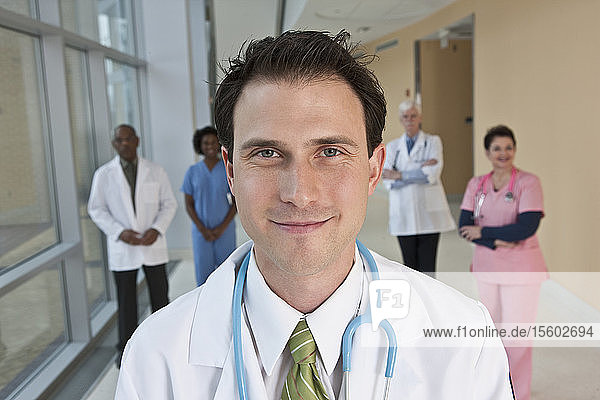 Lächelnder Arzt mit seinen Kollegen im Hintergrund