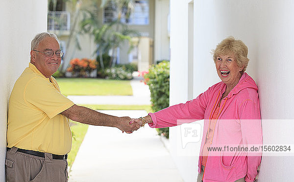 Älteres Paar lächelt an der Tür und hält sich an den Händen