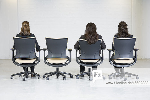 Rückansicht von Geschäftsfrauen  die auf Bürostühlen sitzen.