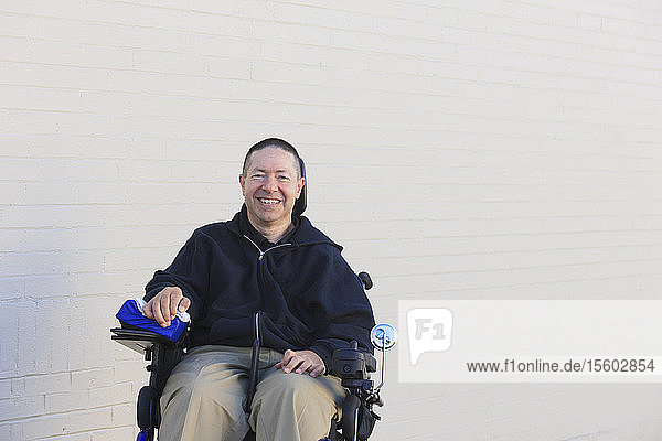 Mann mit Rückenmarksverletzung und Arm mit Nervenschaden im motorisierten Rollstuhl