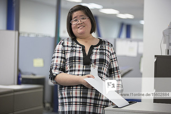 Asiatische Frau mit einer Lernbehinderung arbeitet in einem Büro