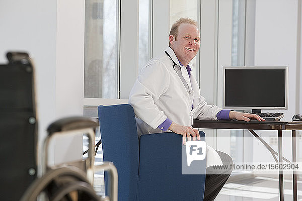 Doctor sitting in front of a computer and smiling