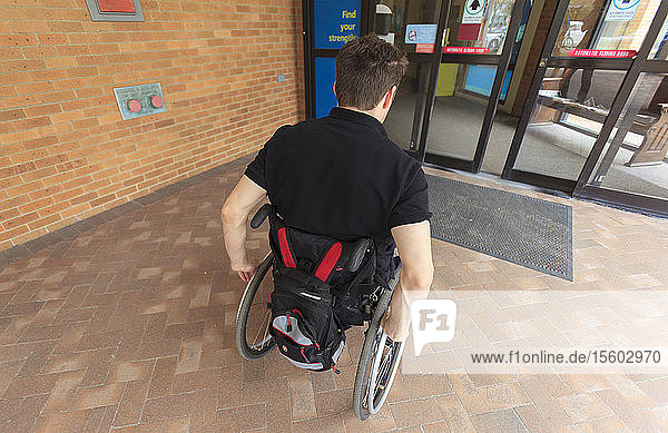 Man with spinal cord injury entering electronic door