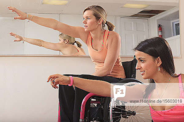 Young women with spinal cord injuries stretching in a yoga studio