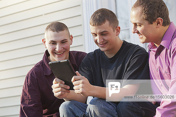Three brothers reading a digital tablet