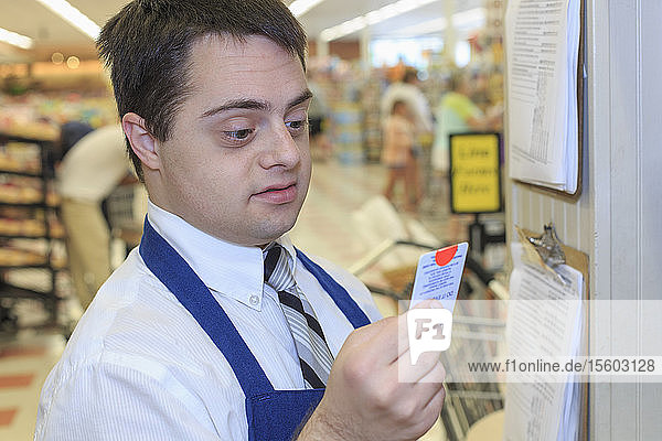 Mann mit Down-Syndrom bei der Überprüfung seines Arbeitsplans in einem Lebensmittelladen