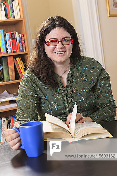 Woman with Asperger syndrome relaxing with a mug of tea and a book