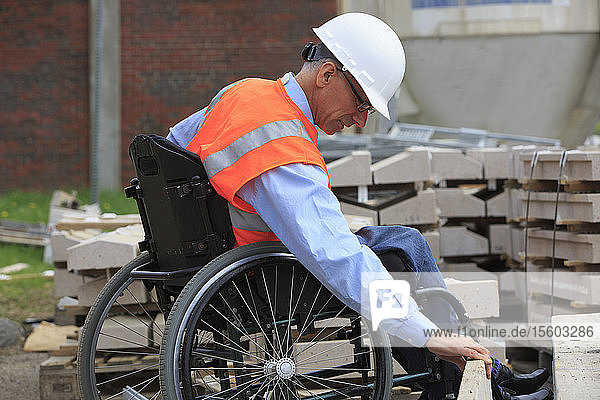 Projektingenieur mit einer Rückenmarksverletzung im Rollstuhl bei der Kontrolle der Baustelle