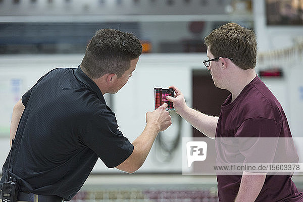 Young man with Down Syndrome working at college testing PH in swimming pool with supervisor
