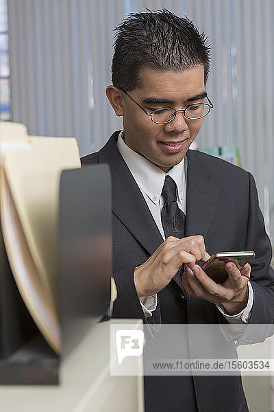 Happy Asian man with Autism using his phone in an office