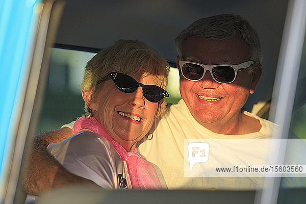 Porträt eines glücklichen älteren Paares  das in einem Auto sitzt