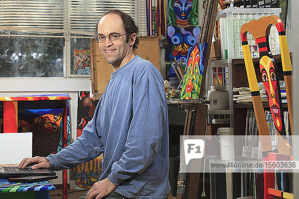 Mann mit Asperger-Syndrom bei der Arbeit an seinem Computer in seinem Kunstatelier