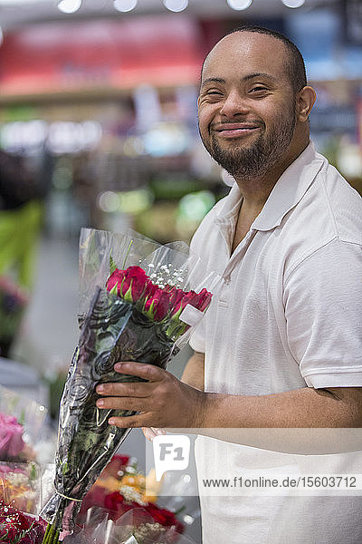 Mann mit Down-Syndrom pflückt Blumen in einem Geschäft
