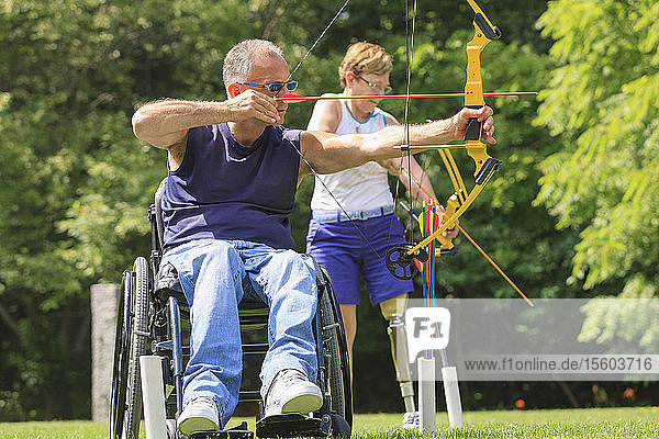 Man with spinal cord injury and woman with prosthetic leg during archery practice