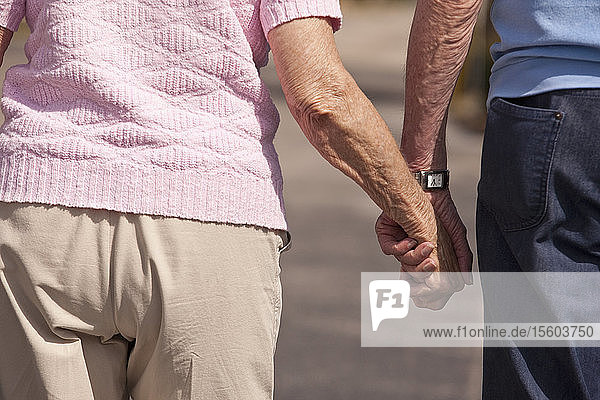 Mid section view of a couple walking with holding hands